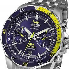 A close-up of the VOSTOK Europe Automatic Watch for Men Rocket N1 NE57-225A563 showcases its blue dial, yellow accents, chronograph dials, stainless steel strap, date display, and 200m water resistance.